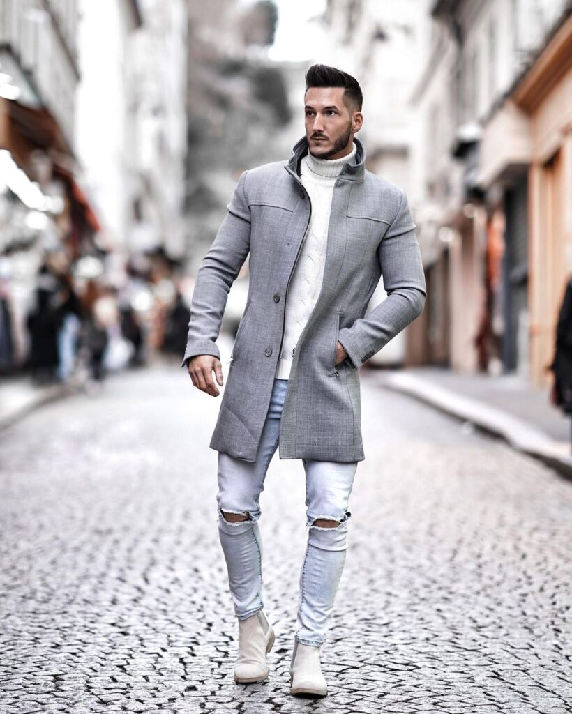 Guy in ripped jeans with a long coat over a hoodie